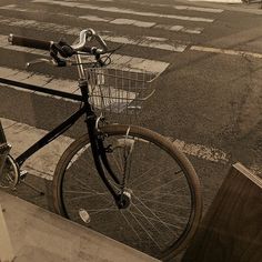 a bicycle parked on the side of a street next to a cross walk with a basket