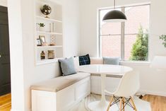 a room with a white table and some chairs next to a bench in front of a window