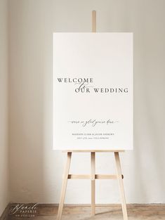 an easel with a welcome wedding sign on it in front of a white wall