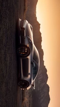 a silver sports car parked on the side of a road next to a rocky cliff