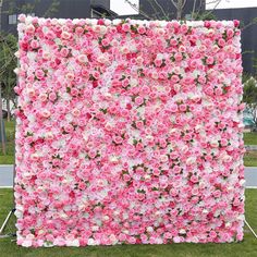 a pink and white flower wall in the grass