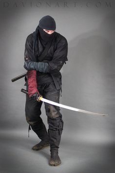 a man dressed in black holding two swords