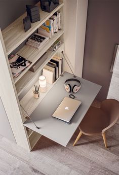 a laptop computer sitting on top of a desk next to a book shelf filled with books