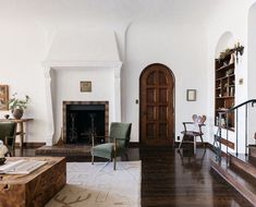 a living room filled with furniture and a fire place next to a wooden floored staircase