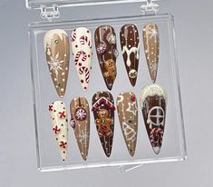 Embrace the warmth and sweetness of the holiday season with this adorable Gingerbread Christmas Press-On Nail Set! Each nail is carefully designed to capture the magic of Christmas with gingerbread houses, candy canes, snowflakes, and festive decorations. Perfect for holiday gatherings, cozy nights in, or adding a cheerful touch to your winter look! ️ 🍪 Gingerbread House and Man Accents Bring the holiday spirit to life with charming gingerbread house and gingerbread man designs! These playful accents make your nails look like mini Christmas treats, adding a unique, joyful vibe to your holiday ensemble. 🍭 Candy Cane and Peppermint Details Festive candy cane stripes and peppermint swirls add a sweet touch to this holiday nail set. These classic Christmas symbols bring a pop of color and fu Christmas Nails Gingerbread House, Extravagant Christmas Nails, Gingerbread House Nail Art, Present Nails Christmas, Ginger Bread Nail Designs, Christmas Cookie Nails, Christmas Nails Brown, Gingerbread Cookie Nails, Nail Noel Christmas