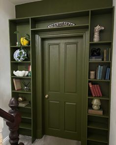 a green bookcase filled with books next to a doorway