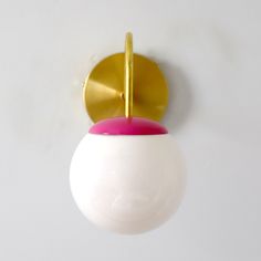 a white and pink object hanging from a gold plated hook on a white wall