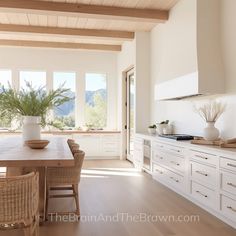 a kitchen with white cabinets and wooden floors, along with a dining table surrounded by wicker chairs