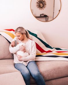 a woman sitting on a couch holding a baby