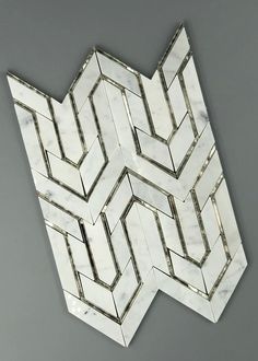 a white and silver wall mounted mirror on a gray wall with an abstract design in the middle