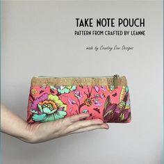 a hand holding a pink floral purse with the words take note pouch pattern from crafted by leane