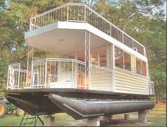 a house boat is sitting in the water with a deck on it's side