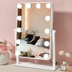 a white vanity mirror sitting on top of a table next to a vase with flowers