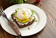 an open faced sandwich with eggs and cucumbers on it next to a knife and fork