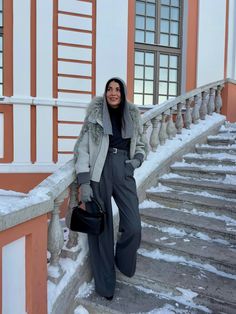 a woman is standing on the steps in front of a building with snow all around her