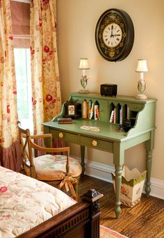 a room with a bed, desk and clock on the wall in front of it