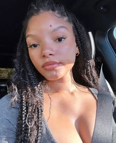 a woman with very large breast sitting in the back seat of a car, looking at the camera