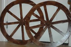 two large wooden wheels sitting next to each other on top of a hard wood floor