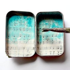 an open tin box with music notes on it and a paintbrush in the middle