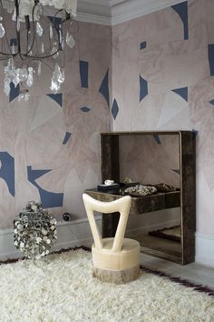 a room with a mirror, chair and chandelier hanging from the ceiling in front of it