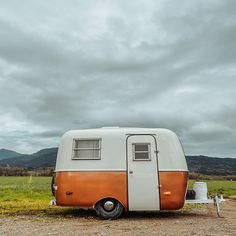 an orange and white trailer parked in the middle of a field