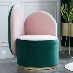 a pink and green chair sitting on top of a floor next to a potted plant