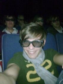 a man wearing sunglasses and scarf sitting in front of an audience at a movie theater