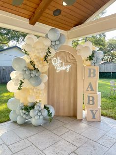 balloons and greenery decorate the entrance to a baby's first birthday party