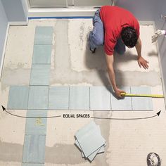 a man laying tile on the floor with measuring tape around it and an equal width between two tiles