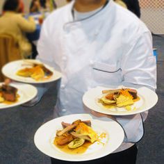 a chef holding three plates with food on them