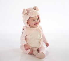 a baby is wearing a pink outfit and smiling at the camera while sitting on the floor