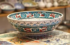 a colorful bowl sitting on top of a table next to other plates and bowls in the background