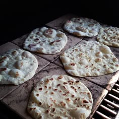 several flat breads are cooking on an outdoor grill