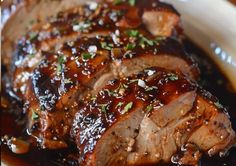 sliced pork with sauce and garnish in a white bowl