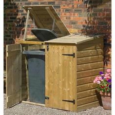 a large wooden storage box next to a brick wall and flower potted planter