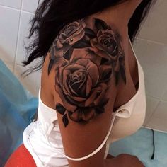 a woman's shoulder with black roses on the back of her arm and chest