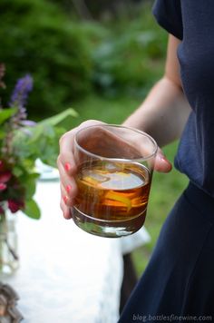 a woman holding a glass filled with liquid