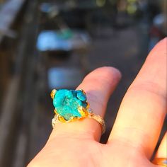 a hand holding a ring with a large blue stone on it's middle finger