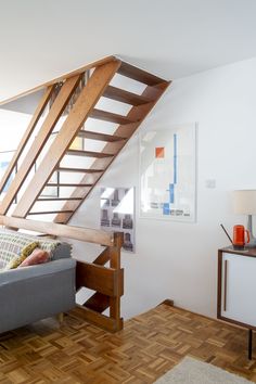 a living room with a couch and wooden stair case next to a wall mounted painting