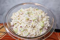 a glass bowl filled with coleslaw on top of a checkered table cloth