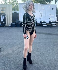 a woman in black and white bodysuit standing on pavement