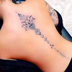 a woman's lower back tattoo with flowers and leaves on her left side ribcage