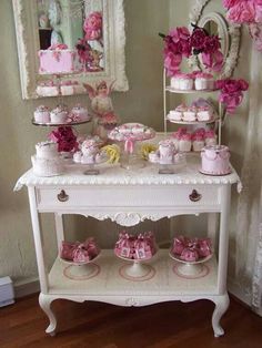 a white table topped with lots of pink cakes and cupcakes on top of it