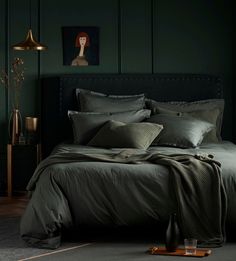 a bedroom with dark green walls and bedding