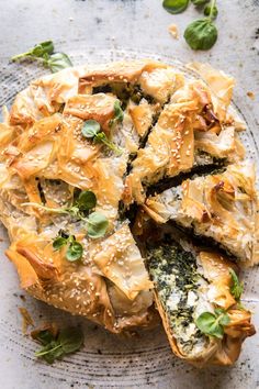 a pie with spinach and cheese on top is cut into pieces to be eaten