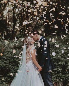 a bride and groom are kissing in front of confetti falling from the trees