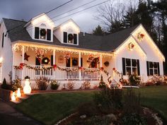 a white house with christmas decorations on the front porch and side windows at night time