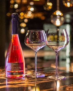 two wine glasses and a bottle on a table