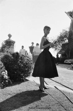 a woman in a dress is standing on the side walk