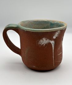 a brown and green cup with white flowers on it